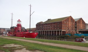A former lighthouse ship moored in the canal and empty warehouses on the other side of the canal